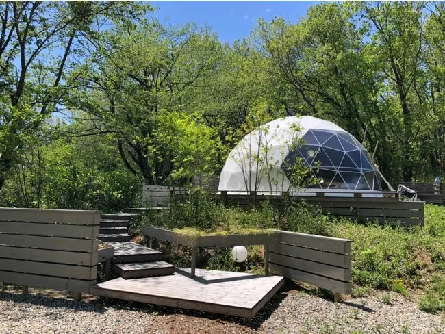 紫塚ゴルフ倶楽部にあるKAKUREGAのドーム型グランピングテントと木製デッキ。森林に囲まれた静かな宿泊空間。