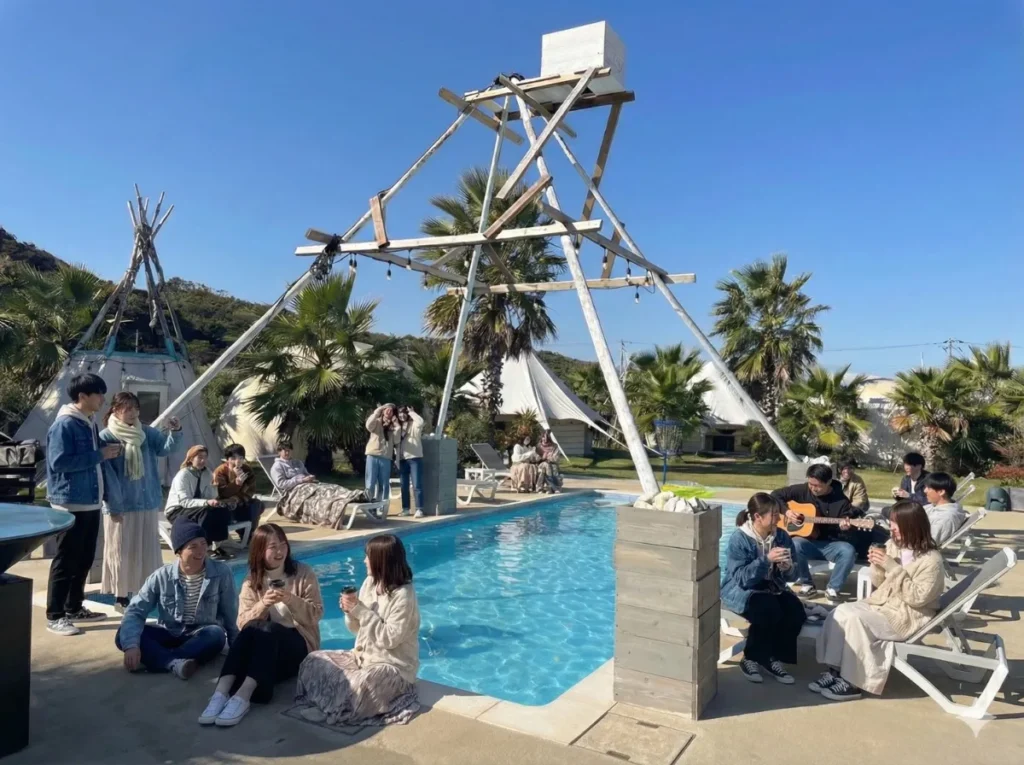 卒業旅行|貸切プールサイドで過ごすOASIS-OARAIの昼 - 茨城・大洗ひたちなかエリアのグランピング施設 Water front Villa OASIS大洗 卒業旅行の仲間が貸切のプールサイドで音楽と会話を楽しむ様子