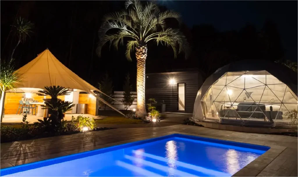 +RIVERPOOL|夜の温水プールとドームテント - 茨城・大洗ひたちなかエリアのグランピング施設 Water front Villa OASIS大洗 +RIVERPOOLの夜の温水プールとライトアップされたドームテント、アウトドアダイニングが並ぶラグジュアリー空間